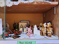 Full view of assorted salt and pepper shakers including animal figurines and paired Eskimo-like figures on a bench.
