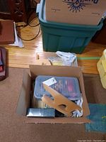 View into box showing wooden yarn swift resting on top of a container filled with supplies.