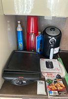 Kitchen counter view displaying Dash air fryer, T-Fal table grill, and SodaStream with accessories.