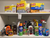 Photo showing cleaning sprays, polishes, and various aerosol cleaning products on a shelf with garbage bags on the upper shelf