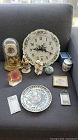 Overview of all items including clocks, plates, figurines, and decorative pieces arranged on sofa
