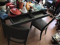 Dining table showing the open storage drawers underneath the tabletop and two of the four upholstered chairs.