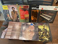 Photo showing nine assorted vinyl records arranged on floor with covers visible, mostly classical genre with artists and titles visible.