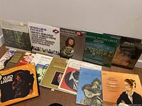 Wide view of 15 assorted vinyl record covers laid out showing classical, opera, jazz and other genres.