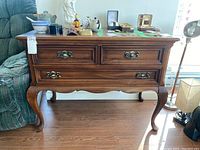 Front view of solid cherry wood console table with three drawers and brass handles.