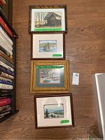 Four framed artworks laid flat on the floor showing a collection of landscape scenes and one watercolour.
