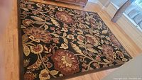 Full view of the area rug showing floral pattern and dark background.