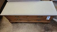 Full view of the Lane upholstered cedar love chest with a diamond pattern upholstered top and faux drawer front.