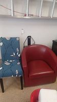 Two chairs displayed side by side: red swivel bucket chair and blue floral fabric armless chair with cover.