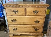 Front view showing all four drawers and decorative brass handles, with visible wood grain and molding detail at the top and base.