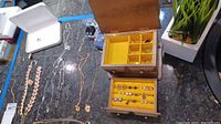 Overhead view of chain necklaces laid out on countertop beside open wooden jewelry box