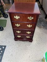 Full view of wooden 4-drawer chest nightstand showing shape, finish and drawer pulls