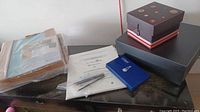 Boxes and papers on a table, showing two large boxed organizers sealed and one smaller box with photo writing pencils on top.