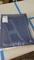 Photo of the blue Creative Memories scrapbooking album sealed in plastic with gold foil corner accents visible