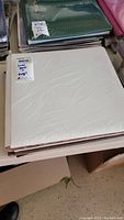 Stack of scrapbooking albums including white album on top, also visible green album beneath, wrapped in plastic.
