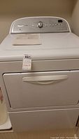 Front view of white Whirlpool Cabrio dryer with control panel and manual on top.
