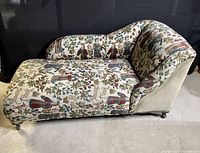 Front and angled view of the antique fainting couch showing the medical motif fabric upholstery with human figures, flowers, and anatomical drawings.