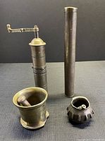 Front view of all four antique items showing the pestles inside the mortars and the spice grinder crank detail