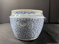 Front view of porcelain pot showing floral pattern and geometric band near the rim with one lion mask handle visible