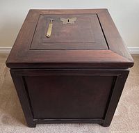 Front view of the blackwood money box showing the brass bat lock on the lid and brass key placement