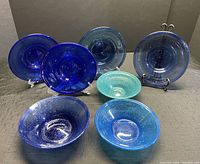 Seven pieces of hand blown Egyptian glass in various shades of blue displayed, 4 plates and 3 bowls.
