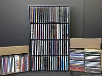 Full view of overall assortment of music CDs in jewel cases and box sets, displayed in racks and stacked in boxes, many with visible spines of various artists.