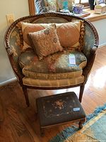 Full view of carved armchair with cushions and needlepoint ottoman