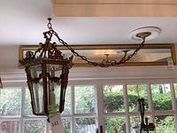 Full view of hanging lamp suspended by chain showing hexagonal shape and window behind
