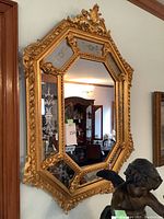 Front view of octagonal gilded mirror hung on wall, full frame visible