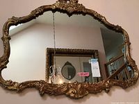 Front view of rectangular mirror with ornate carved wood frame and gold gilt finish