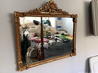 Full view of ornate gold gilt rectangular wall mirror hung on wall