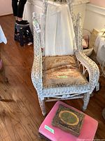 Front view of white wicker rocking chair with cushion and draped throw