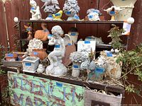 Front view showing multiple statues and pots arranged on metal shelves with French market sign.