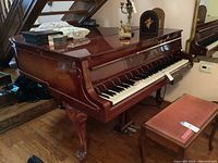 Full view of piano and matching bench under staircase