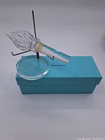 The crystal decanter stopper resting on a black metal holder above a Tiffany & Co. blue box, showing the overall item and packaging without stand.