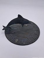 Front view of sundial showing dolphin figure and Roman numerals on dial