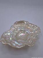 Top and angled view of a layered, irregularly shaped iridescent glass serving dish with a pearlescent shine.