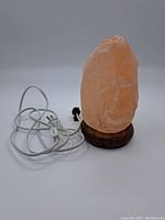 Himalayan salt lamp assembled with salt rock on wooden base and attached electrical cord with switch and plug.