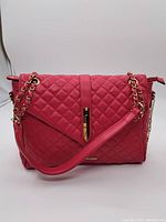 Front view of the red quilted handbag with gold chain strap and clasp.