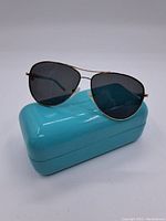 Front view of aviator sunglasses resting on closed Tiffany blue hard case