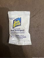 Front of a single Soft Scrub Automatic Dish Detergent packet with brand name and usage instructions.