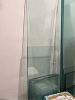 Four thick glass shelving panels leaning against a wall, various sizes visible, edges polished