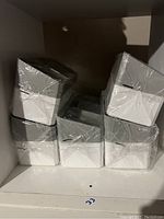 Stacked view of five plastic cosmetic organizers wrapped in plastic, showing white and gray sections.