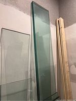Eight clear glass shelves leaning against a wall, showing length and thickness.
