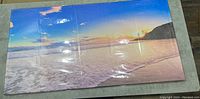 Front view of the canvas print showing the beach sunset landscape scene covered in protective plastic.
