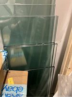 Stacked clear glass shelving panels showing thick edges and varying sizes.