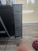 Front view of the narrow storage unit showing four fabric drawers with front handles and steel frame.