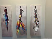 Full view of all three oil paintings hung on a wall, showing abstract female figures in colorful dresses