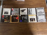 Top-down photo of 10 classical music CDs by Bach arranged in two rows on a wooden surface.