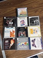 Photo showing 10 classical music CDs laid out on a wooden surface. Covers include themes from Mozart, Wagner, Baroque music, and piano concertos.